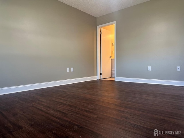 spare room with dark wood-type flooring, baseboards, and a textured ceiling