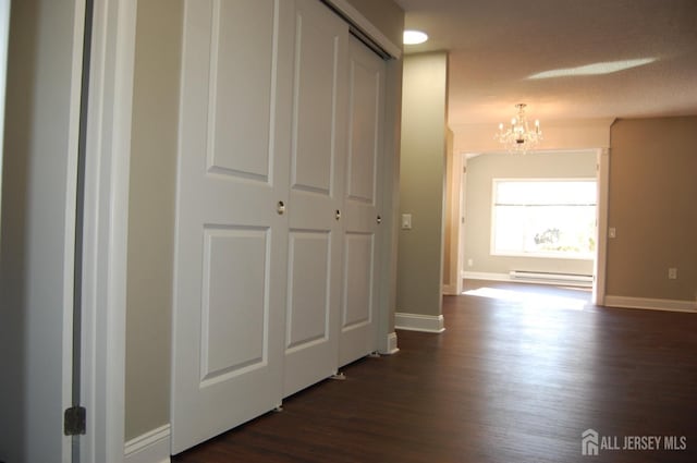 corridor featuring dark wood-style floors, baseboards, an inviting chandelier, and a baseboard radiator