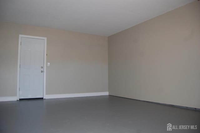 unfurnished room with finished concrete flooring and baseboards