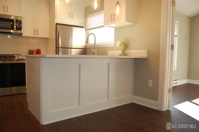 kitchen featuring backsplash, stainless steel appliances, a peninsula, white cabinets, and baseboard heating