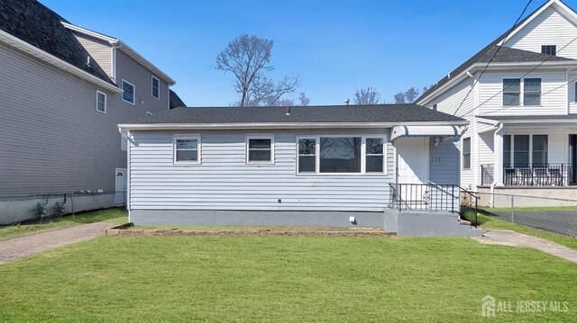 view of front of house with fence, roof with shingles, and a front yard