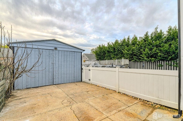 view of patio / terrace with a storage shed, fence, and an outbuilding
