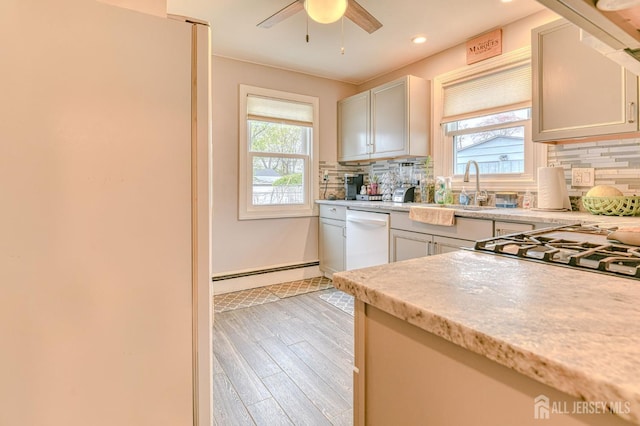 kitchen featuring white appliances, a baseboard heating unit, a sink, tasteful backsplash, and recessed lighting