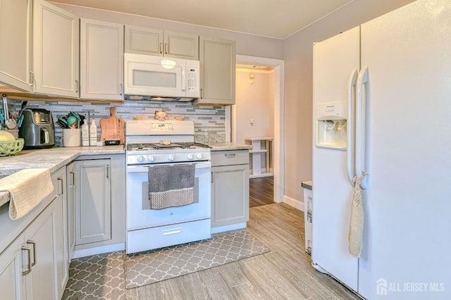 kitchen featuring white appliances, light wood finished floors, light countertops, decorative backsplash, and baseboards