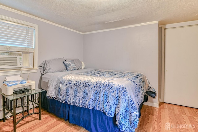 bedroom with wood finished floors, cooling unit, a textured ceiling, and crown molding