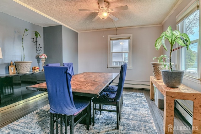 dining space with a textured ceiling, dark wood-style flooring, healthy amount of natural light, ornamental molding, and ceiling fan