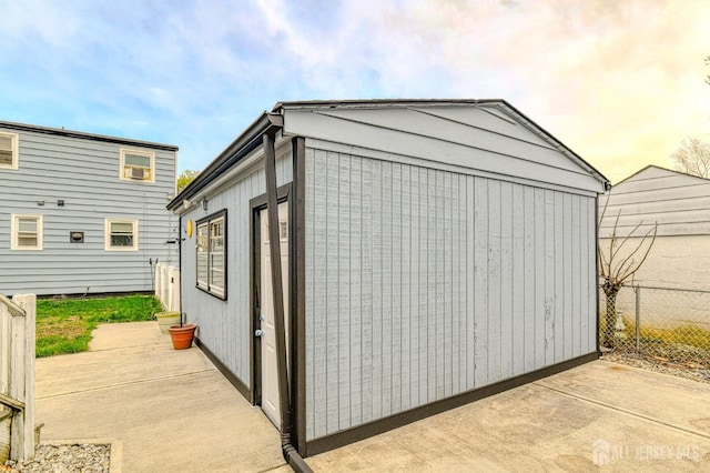 view of outdoor structure with fence and an outbuilding