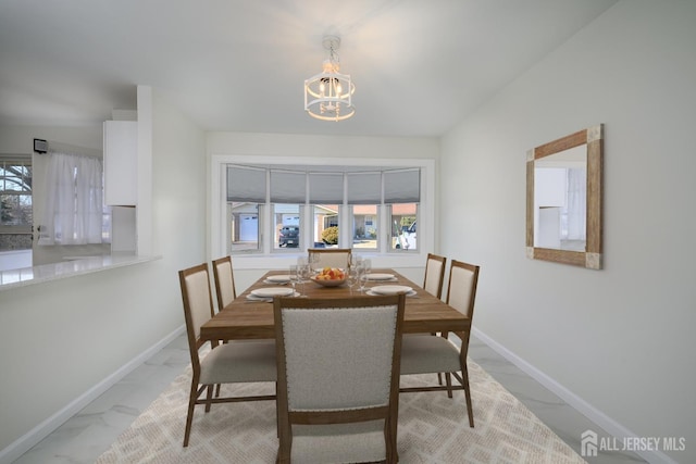 dining space featuring a wealth of natural light, baseboards, a notable chandelier, and marble finish floor