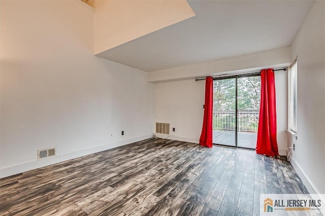 empty room featuring baseboards, wood finished floors, and visible vents