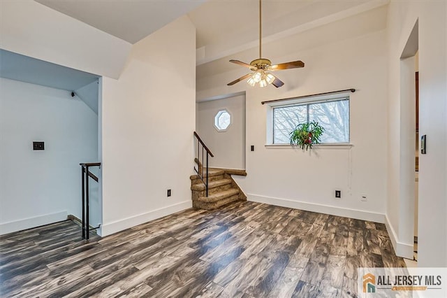 interior space with a ceiling fan, vaulted ceiling, wood finished floors, and stairway
