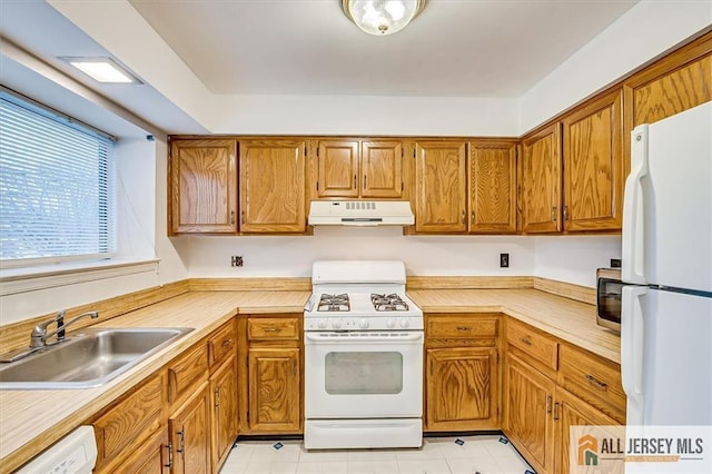 kitchen with white appliances, under cabinet range hood, a sink, and light countertops