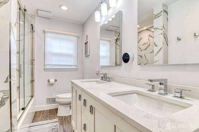1056 Kearney Dr, North Brunswick, NJ 08902 - bathroom featuring double vanity, shower / bath combination with glass door, wood finished floors, and recessed lighting