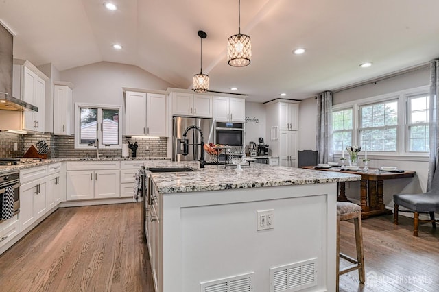 1056 Kearney Dr, North Brunswick, NJ 08902 - kitchen with healthy amount of natural light, light wood-style flooring, white cabinets, vaulted ceiling, and recessed lighting
