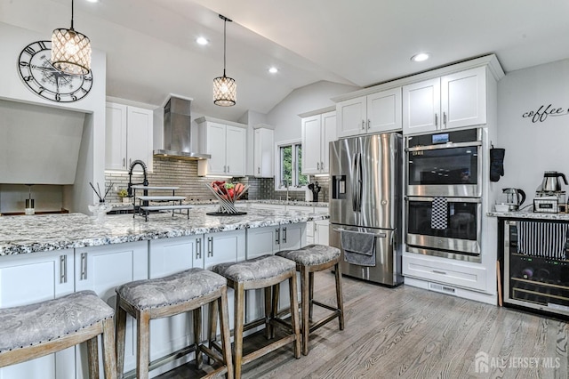 1056 Kearney Dr, North Brunswick, NJ 08902 - kitchen featuring appliances with stainless steel finishes, wall chimney range hood, beverage cooler, vaulted ceiling, and tasteful backsplash