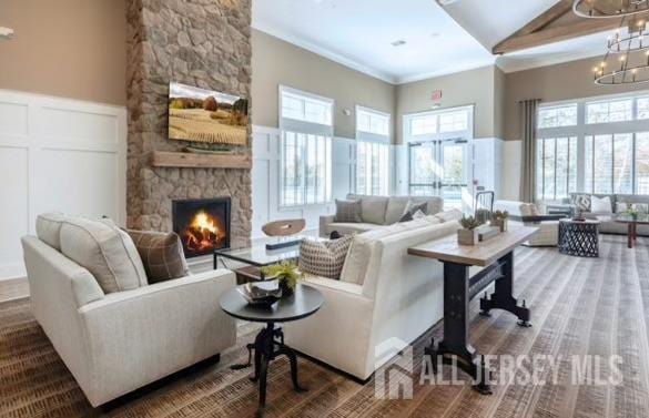 living room with crown molding, wainscoting, a decorative wall, a fireplace, and a notable chandelier