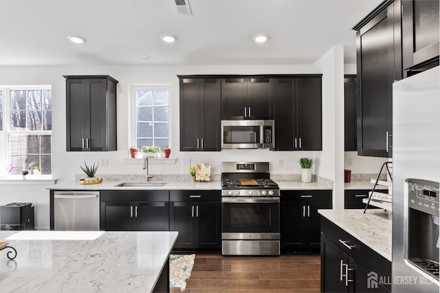 kitchen featuring visible vents, dark cabinets, a sink, dark wood finished floors, and appliances with stainless steel finishes