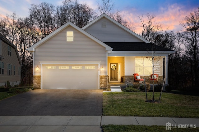 view of front of property featuring a porch, driveway, a front yard, a garage, and stone siding