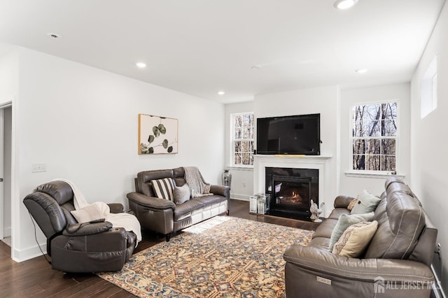 living room with recessed lighting, dark wood finished floors, a glass covered fireplace, and baseboards