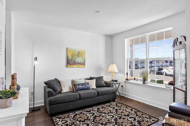 living area with baseboards, dark wood-type flooring, and visible vents