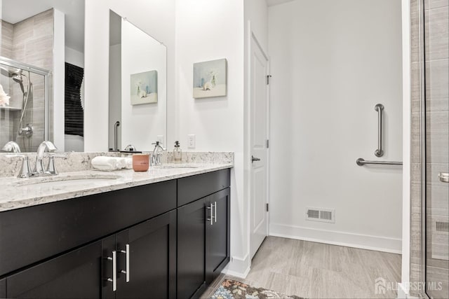 bathroom featuring visible vents, a sink, double vanity, and a shower stall