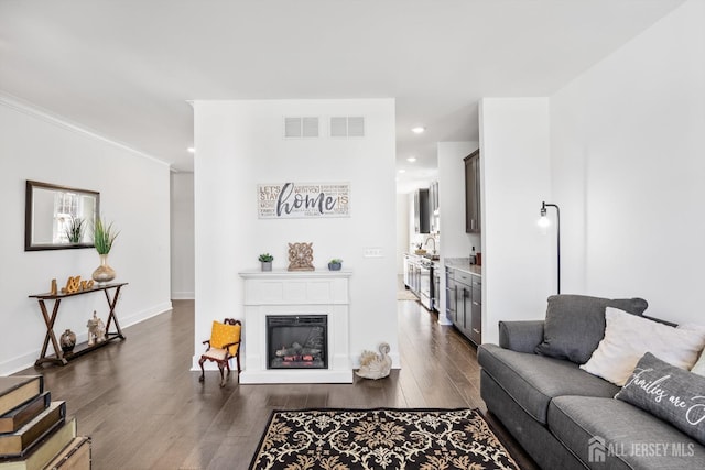 living area featuring visible vents, recessed lighting, dark wood finished floors, and a glass covered fireplace