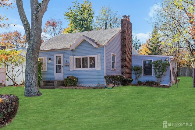 view of front facade featuring a chimney, fence, and a front yard