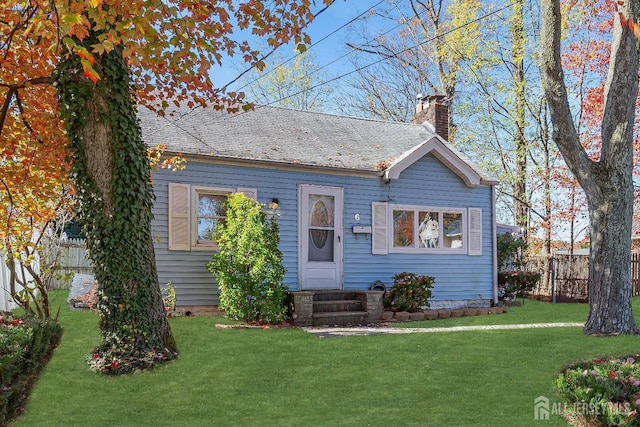 view of front of property featuring entry steps, a chimney, a front yard, and fence