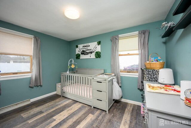 bedroom featuring dark wood-type flooring, a nursery area, baseboard heating, and multiple windows