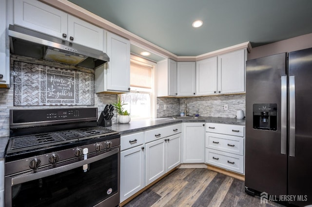 kitchen with decorative backsplash, dark wood-style flooring, stainless steel appliances, under cabinet range hood, and a sink