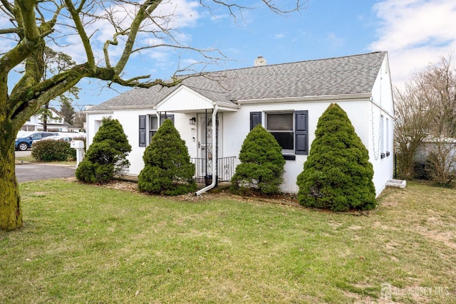 view of front of property featuring a shingled roof, a chimney, and a front lawn