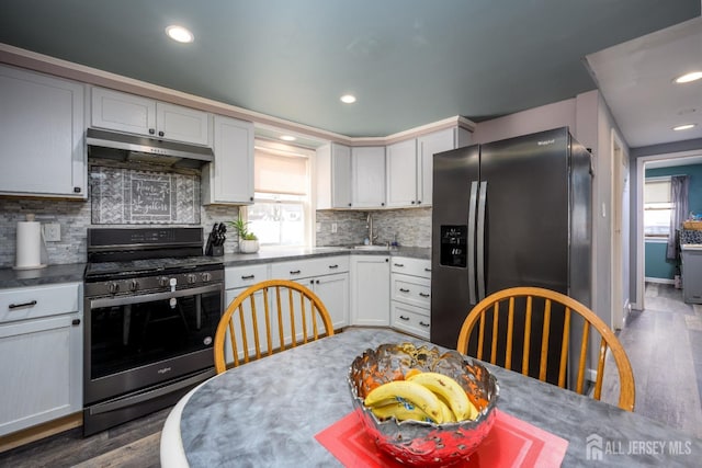 kitchen featuring white cabinetry, appliances with stainless steel finishes, dark hardwood / wood-style flooring, and decorative backsplash