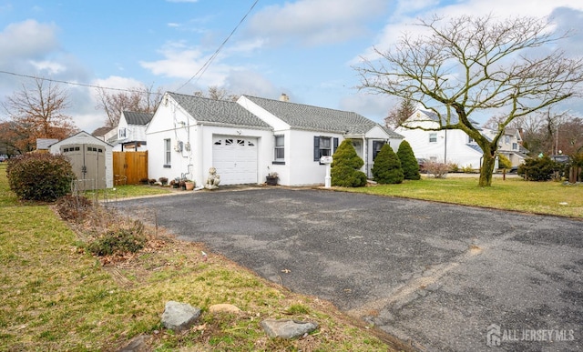 view of front of property with an attached garage, fence, a yard, driveway, and stucco siding