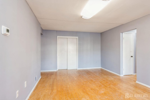 unfurnished room featuring baseboards and light wood-type flooring