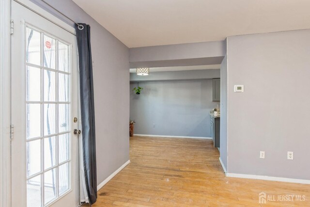 corridor featuring light wood-type flooring and baseboards