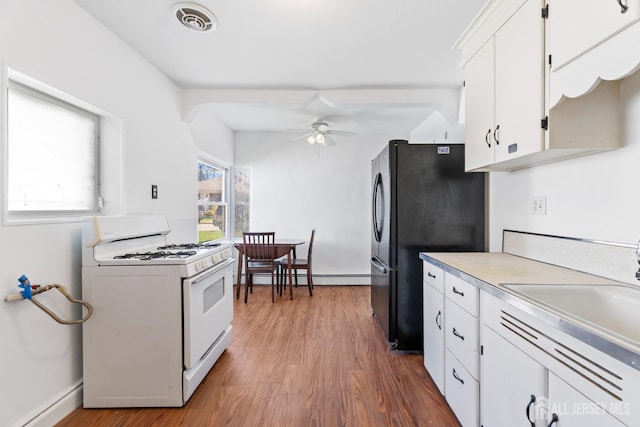 43 Jensen Ave, Fords, NJ 08863 - kitchen featuring freestanding refrigerator, ceiling fan, white gas stove, a baseboard heating unit, and white cabinets