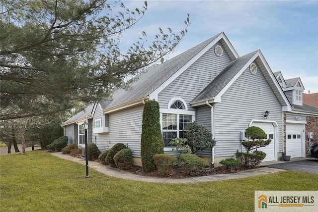 view of side of home with a garage, aphalt driveway, and a lawn