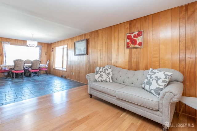 living room with wood walls, a chandelier, and wood finished floors