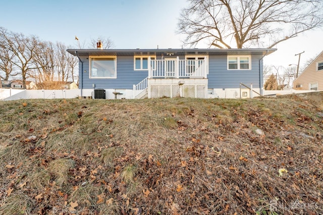 view of front facade with central AC, fence, a chimney, and a wooden deck