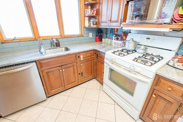 kitchen featuring brown cabinets, decorative backsplash, stainless steel appliances, and a sink