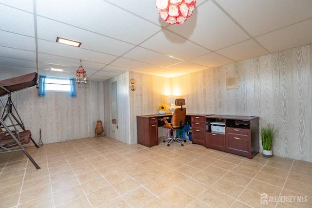 office area featuring a paneled ceiling, light tile patterned flooring, and wooden walls