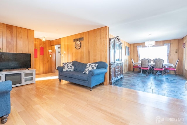 living area featuring wood finished floors, visible vents, wooden walls, and an inviting chandelier