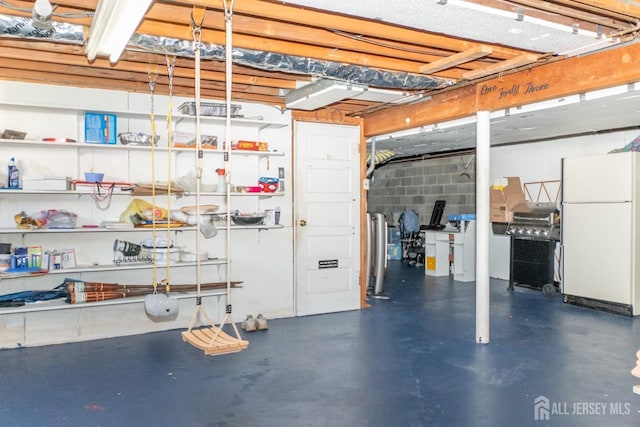 unfinished basement with freestanding refrigerator