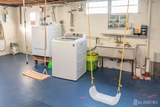 laundry room with laundry area, a sink, concrete block wall, and washer and dryer