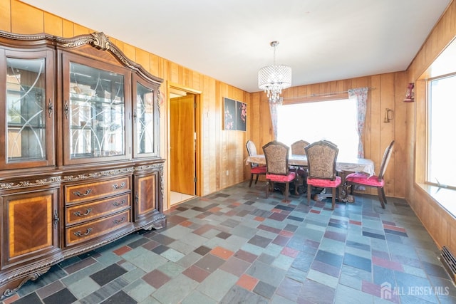 dining space with a notable chandelier and wooden walls