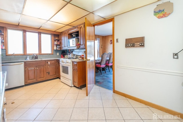 kitchen featuring stainless steel appliances, brown cabinetry, a sink, and open shelves