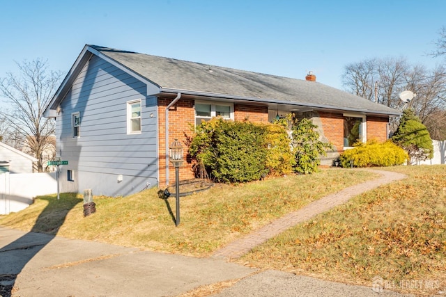 view of front of home featuring brick siding, fence, a chimney, and a front lawn