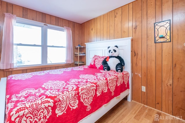 bedroom with wood walls and wood finished floors