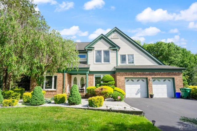 view of front facade with a front yard, a garage, brick siding, and driveway