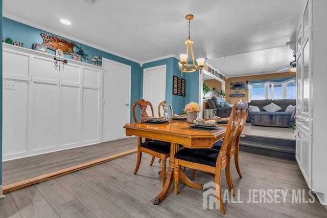 dining space with light hardwood / wood-style flooring, a chandelier, and ornamental molding