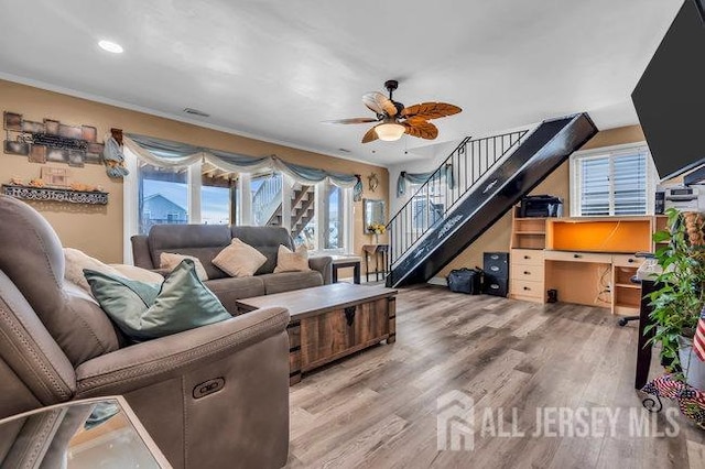 living room featuring hardwood / wood-style flooring, crown molding, and ceiling fan